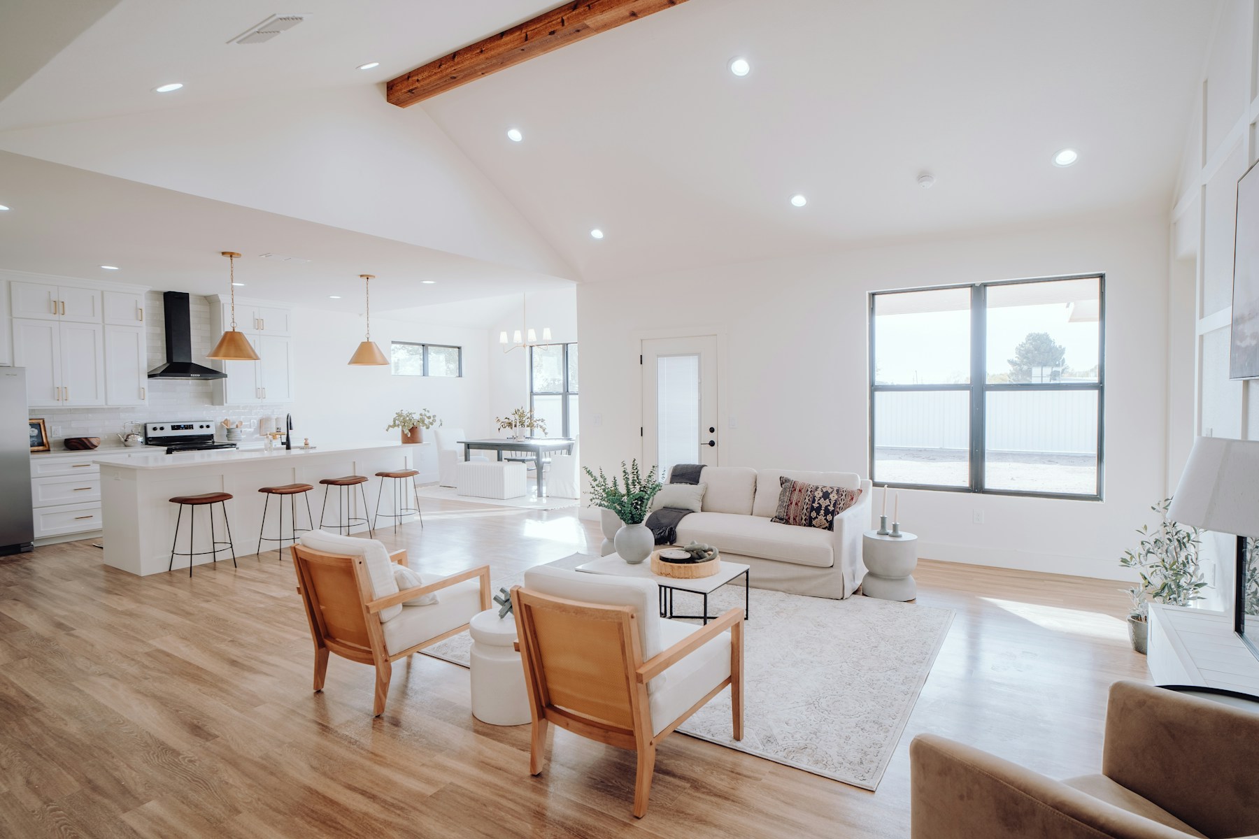 Een lichte woonkamer met houten vloer, een witte bank en een open keuken.